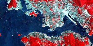 A false color image of Hong Kong Harbor, where the normally green vegetation is a bright red and the more urban buildup is a lighter cyan.