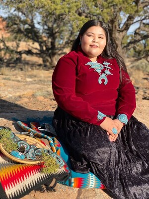 Monica Howard seated on a blue Pendleton blanket wearing traditional Navajo clothing