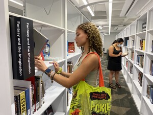 Two people in the library browsing books on the shelves