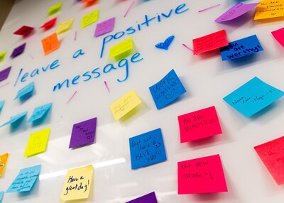 A whiteboard covered with colorful positive message post-it notes
