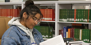 ASU undergraduate student Andrea Luna Cervantes reads in the Scholars Enclave book collection at Hayden Library.
