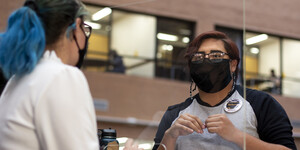 Two people wearing masks talking at the library service desk