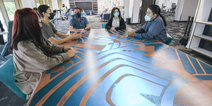 Five Indigenous people of various genders sitting around the O'odham Storytelling Table