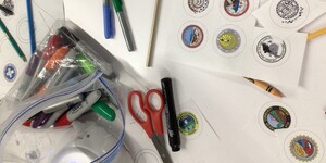 Photo of tribal seals printed out with crayons and markers available on a white table for Indigenous students at SPIRIT program.