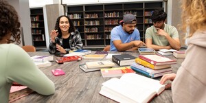 A group of students sitting around a table talking and studying