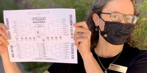 Anali Perry holds up a 2021 March Mammal Madness bracket