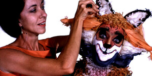 Color photograph of costume/makeup designer Irene Corey adjusting the headpiece on the costumed fox that appeared in the Everyman Players production of Reynard the Fox.