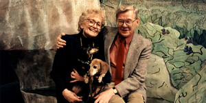A color photograph of Lowell and Nancy Swortzell and their dachshund dogs Lotte and Lenya, sitting in front of the Peter Rabbit and Me by Aurand Harris set for the New York University Educational Theatre production.
