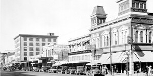 A scene of Washington Street, downtown Phoenix, 1928. Buildings line the street with cars parked along the length of the road.