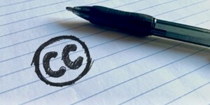 notebook paper with handwritten the CC creative commons logo and a ballpoint pen