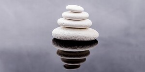 four white stones balanced on top of one another in a stack, largest to smallest
