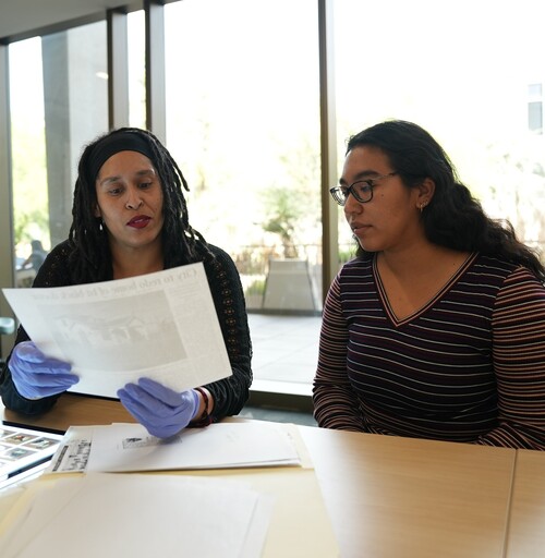 A student and archivist reviewing archival materials together.