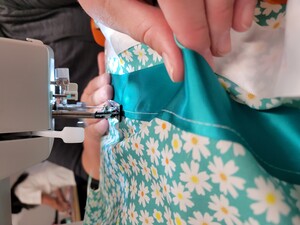 Student using a sew machine to sew blue and white fabric. 