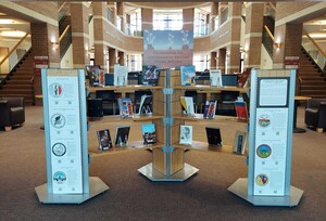 Photo of display at Fletcher Library with title sign in middle and tribal seals on columns. Books from Open Stacks are interspersed on shelves. Tribal Seal signs designed by Ashley Davis (Navajo) and Mafi Pamaka (Tongan).
