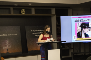 Amber Bleazer-Wardzala reading at podium wearing a dark red shirt and a fabric face mask