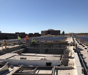 Photo of the roof of Hayden Library, showing the masonry for the top of the new elevator shafts in a sea of solar panels.