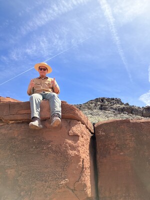 Photo of Eli Shepherd (Dine') sitting on large red rocks