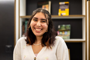 Person standing in front of a bookshelf smiling for the camera