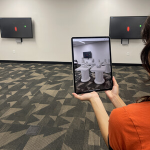 Person holding an iPad displaying a 3D augmented reality museum of objects on pedestals 