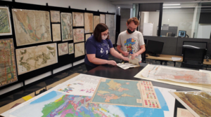 A student worker and staff member inspecting a map in the Map and Geospatial Hub.