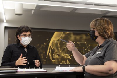 two female librarians wearing face masks discuss their research