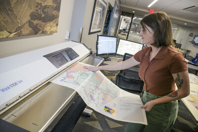 Person feeding a map into a large scanner