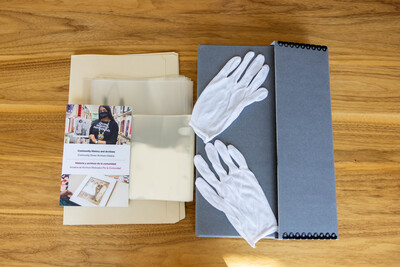Archival starter kit with bilingual preservation brochure and supplies such as an acid-free box, folders, mylar, and gloves.