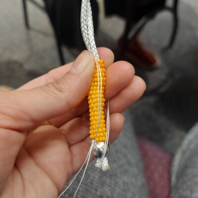 Photo of a yellow beaded chain in progress