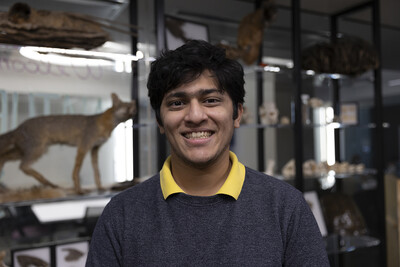 Portrait of student in Naturespace smiling with animal specimens on display in the background