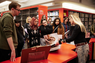 An ASU FIDM Library employee showcasing a large graphic book to a group of students.
