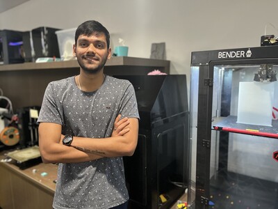 Student standing next to 3D printers in the Makerspace