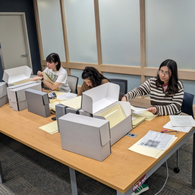 Several people working at a table looking through archival materials and boxes