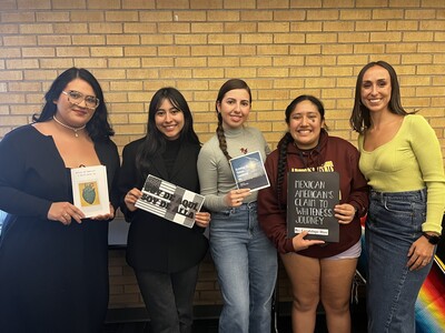 A group of five people standing and holding zine projects smiling for the camera