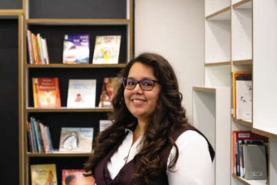 Nancy Godoy poses for a portrait in front of a bookshelf in Hayden Library