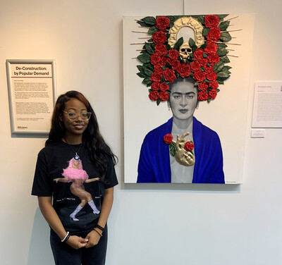 Student standing next to painting of Frida Kahlo artwork