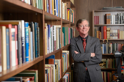 University Librarian Jim O'Donnell standing next to a bookcase full of books